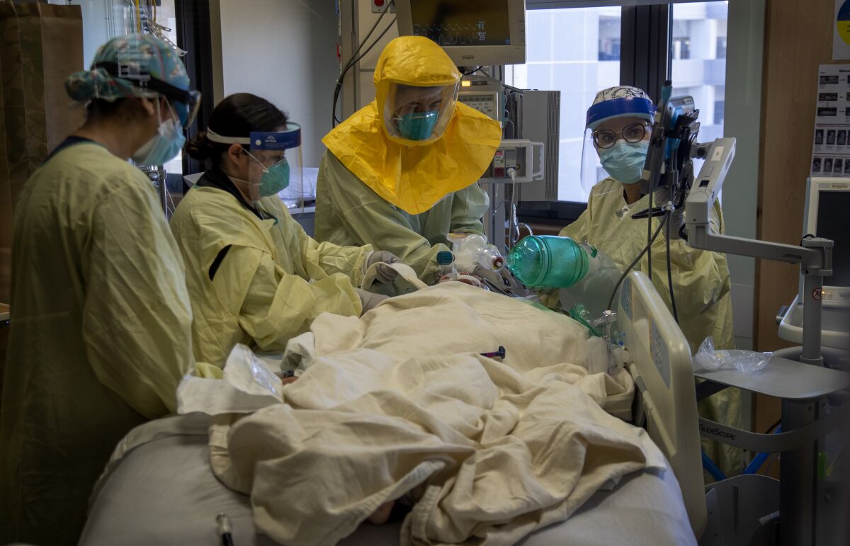 Dr. Laren Tan, center, a pulmonologist, works to intubate a COVID-19 patient Tuesday at Loma Linda University Medical Center.