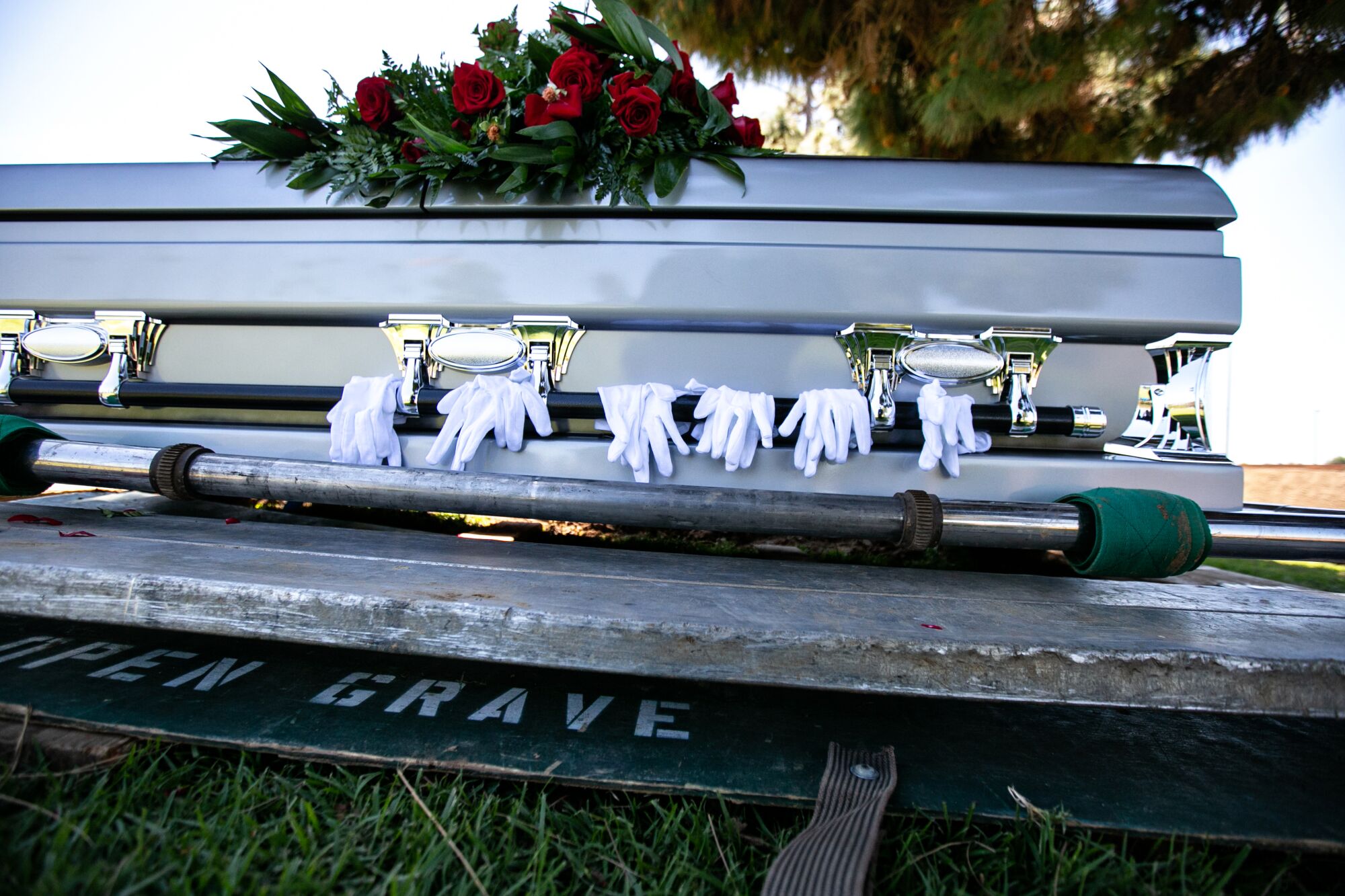 Gloves worn by pallbearers are draped on the casket of Charles Jackson Jr., who died of COVID-19, on April 15 at the Inglewood Park Cemetery in Los Angeles.