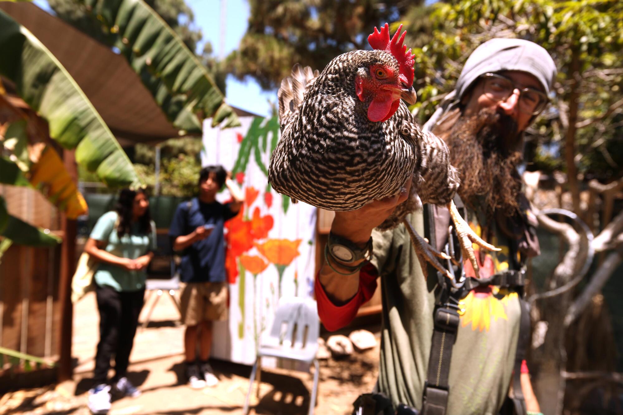 A man holds up a chicken. 