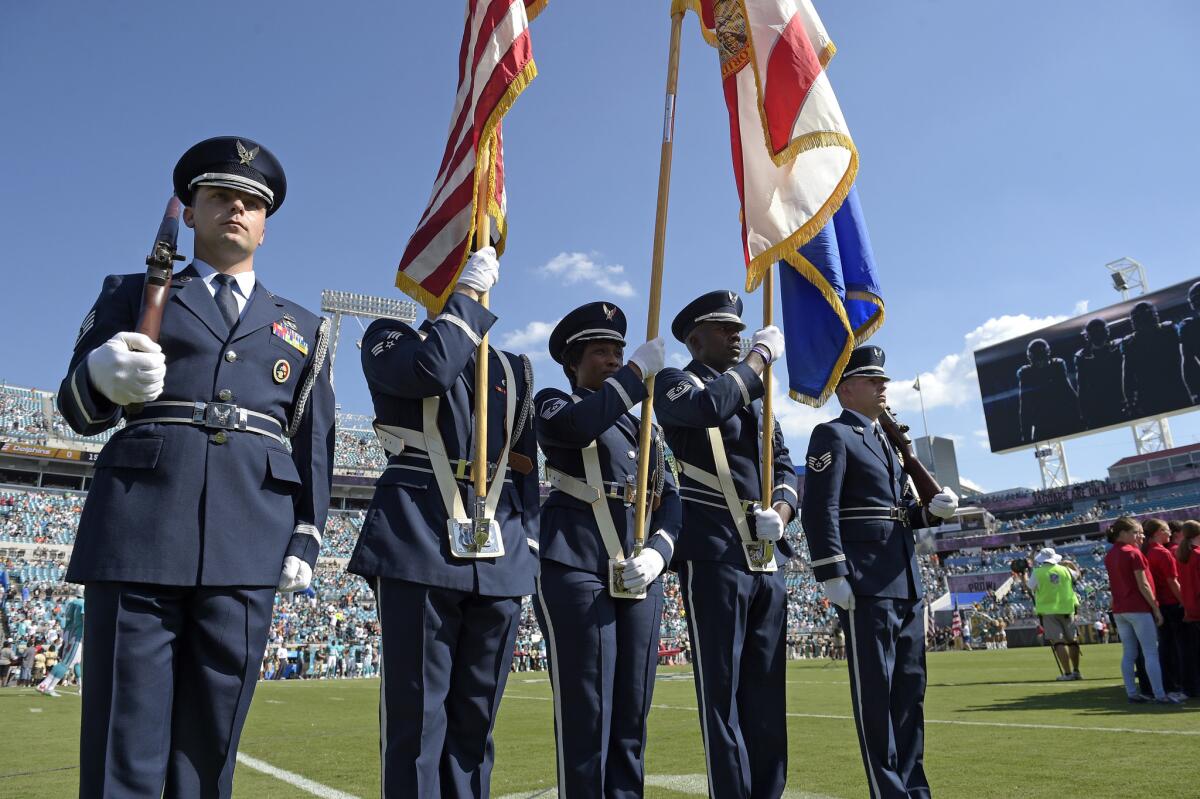 A military color guard stands at attention for the singing of the national anthem before an NFL game between the Dolphins and the Jaguars in Jacksonville, Fla., on Sept. 20, 2015.