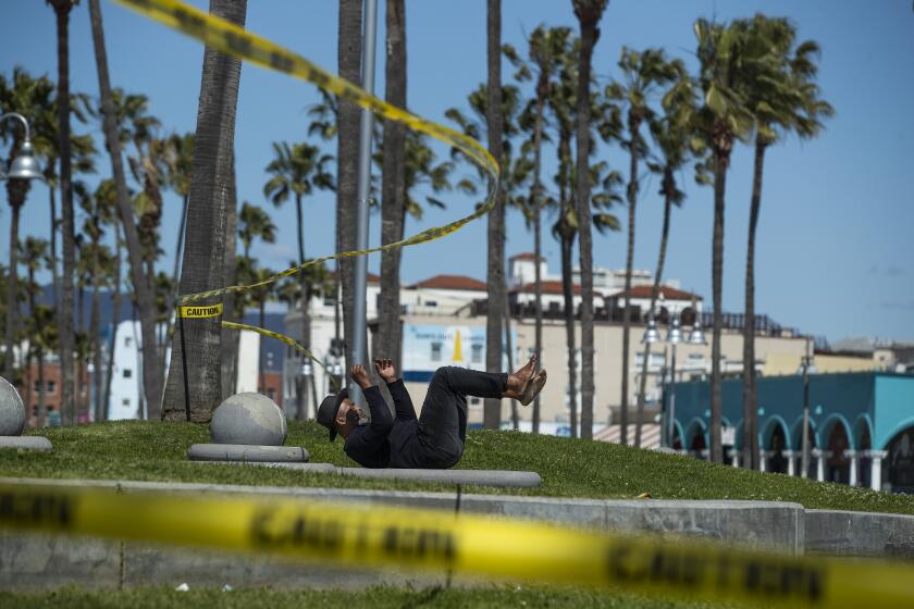 Raymond Bartlett, 53, of Venice, does calisthenics next to yellow caution tape placed near the entrance to the basketball courts at Venice Beach.