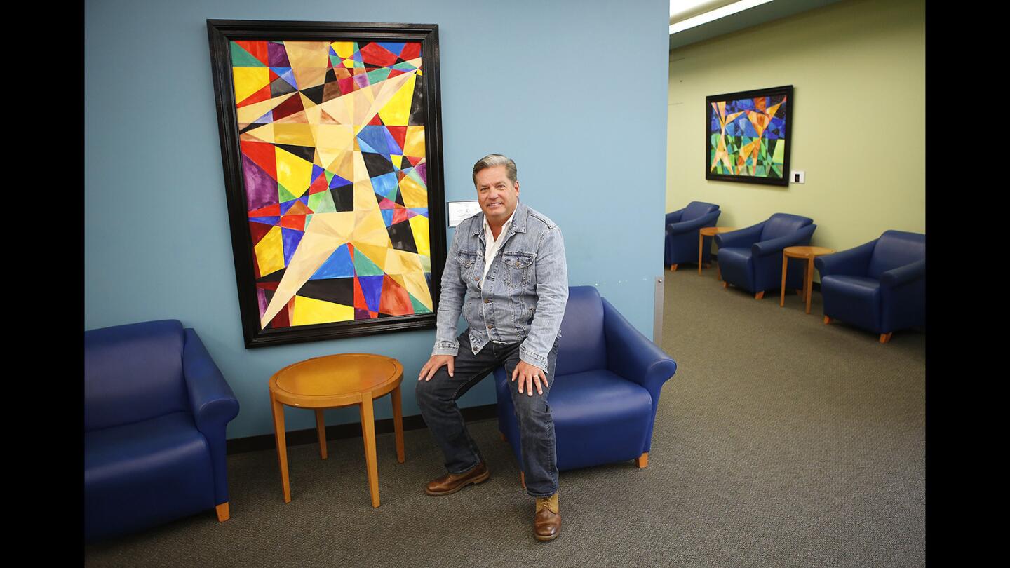 Chip Fesko stands next to one of his vertical abstract geometric paintings, "orthogonal lines to no where", on display at the Newport Beach Central Library.