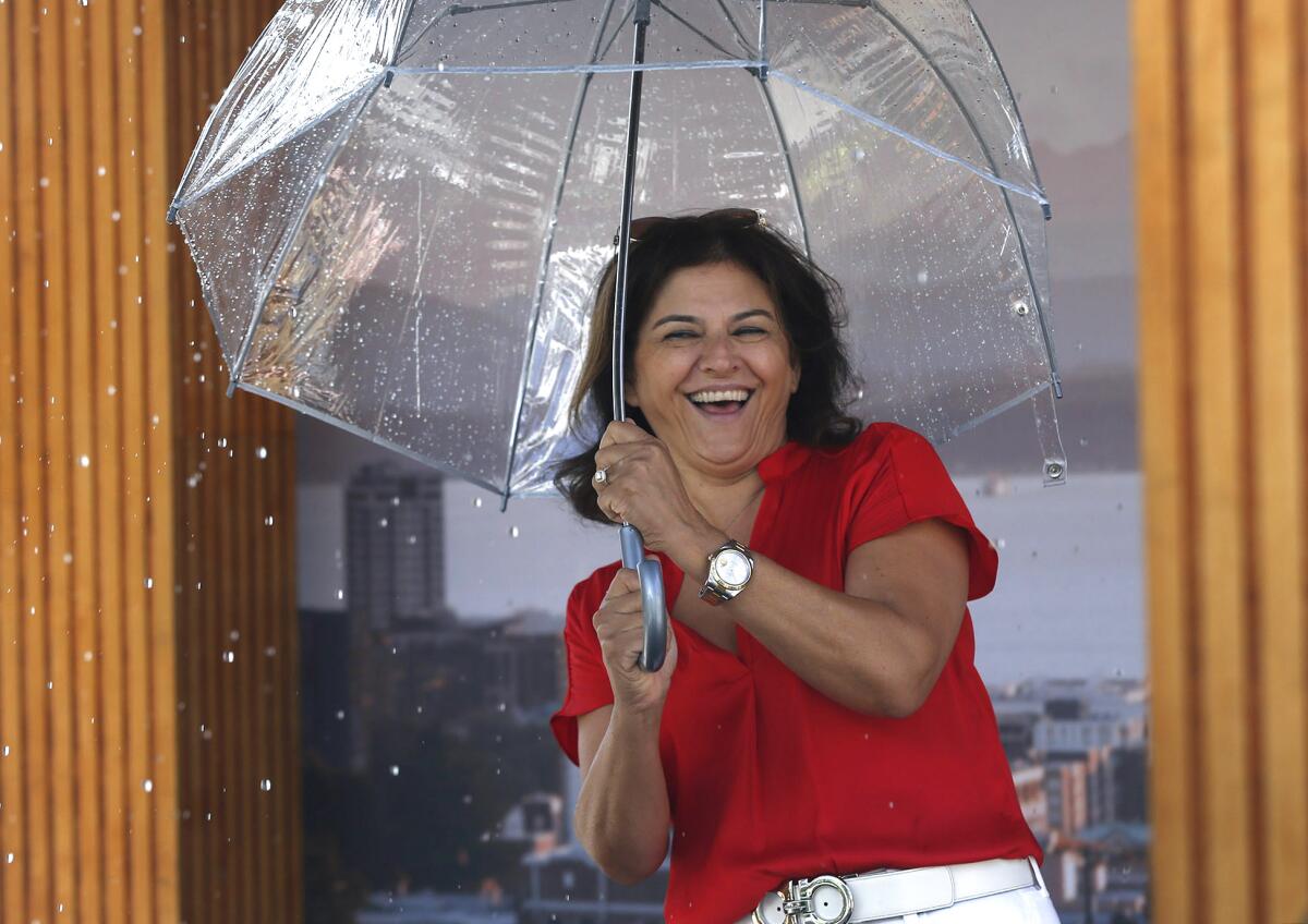 Nancy Aynehchi happily steps into Seattle's famous, traveling rain booth. It next heads to Sacramento.