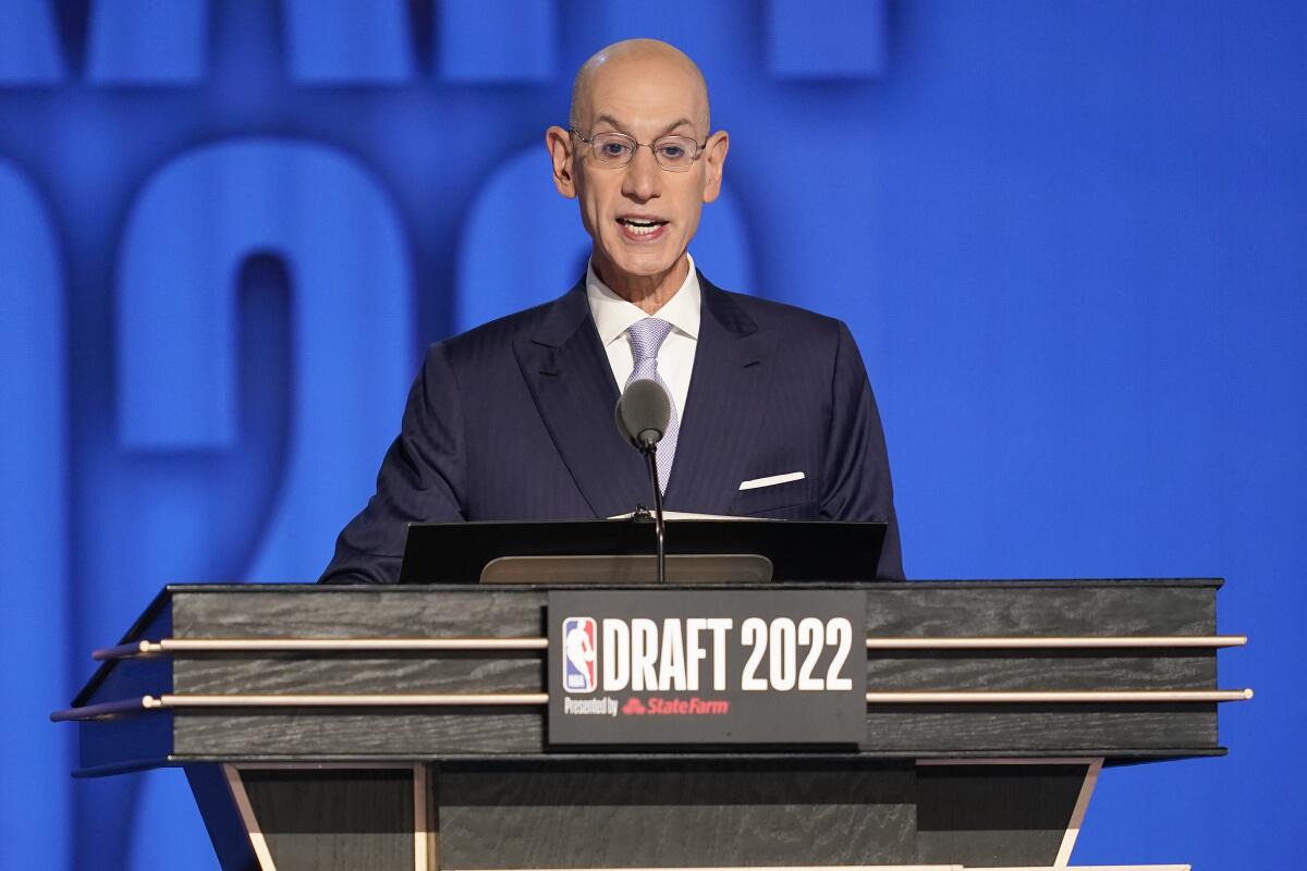 A man, in a head-and-shoulders frame, wearing suit and tie, stands behind a lectern with "Draft 2022" writing on it. 