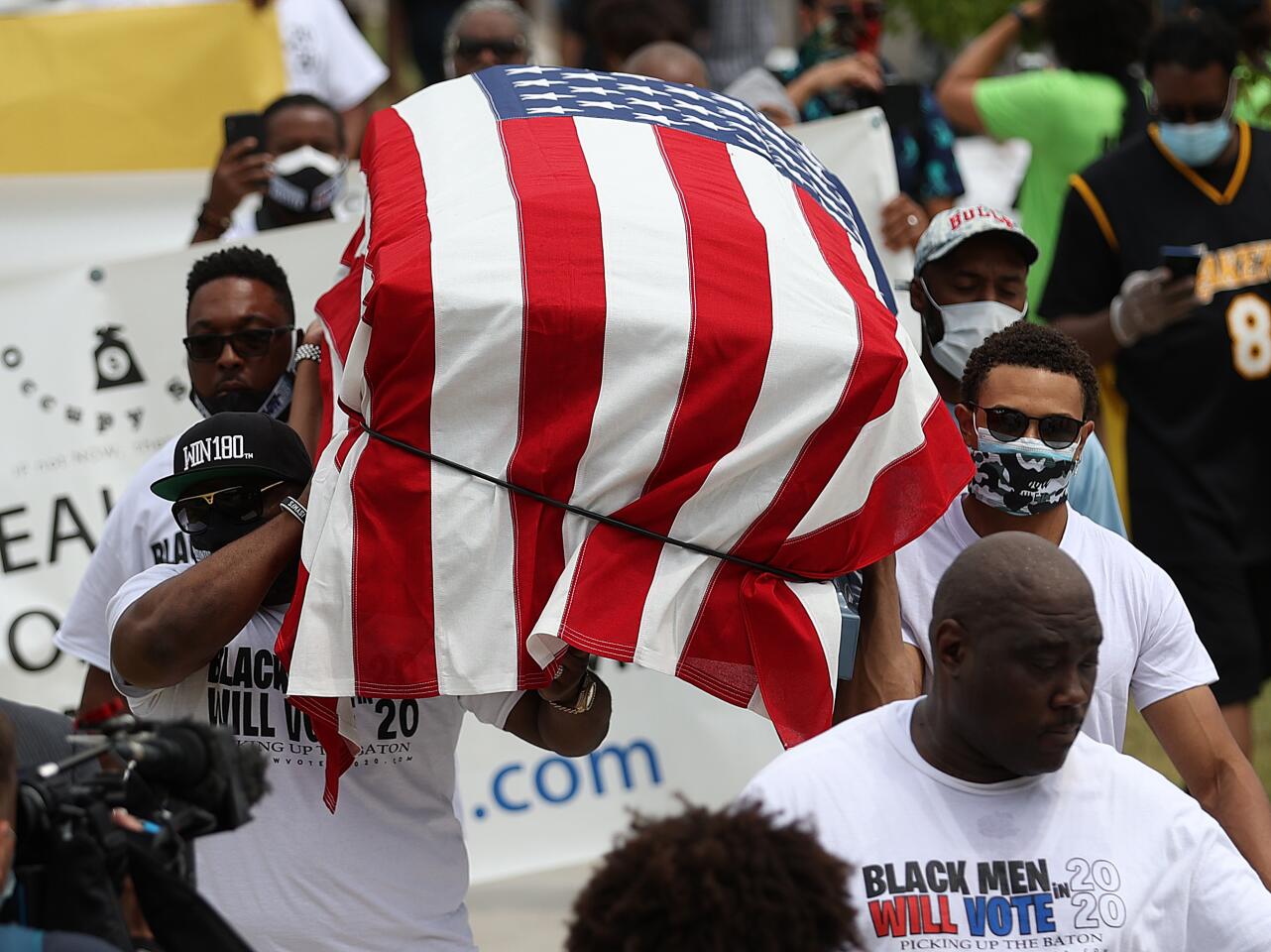 People carry a symbolic casket draped with an American flag during a Juneteenth event in the Greenwood District of Tulsa.