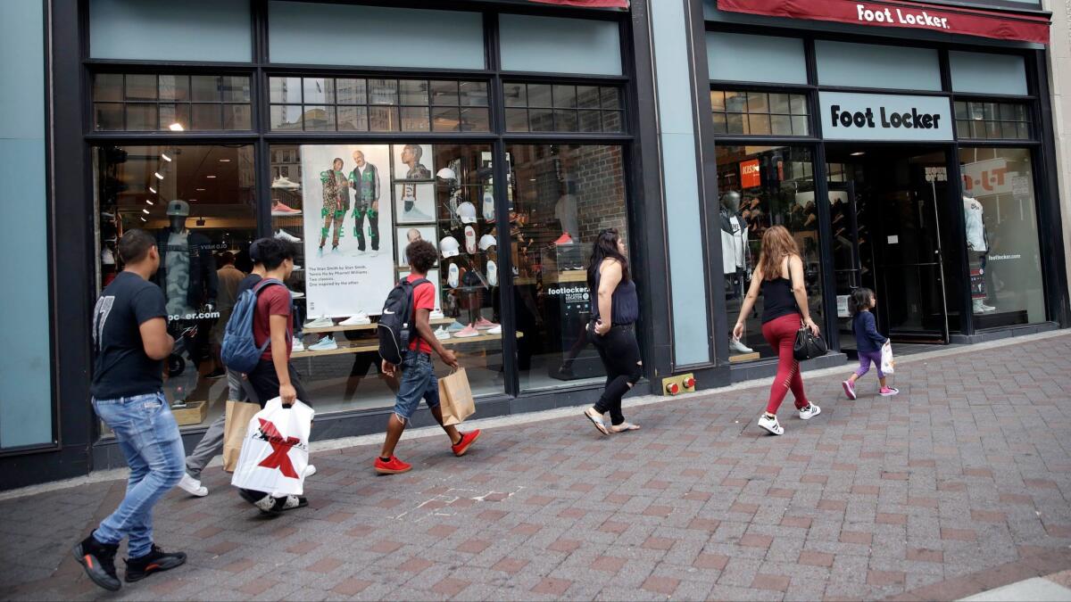Shoppers walk past a Foot Locker store in Boston on Aug. 25.