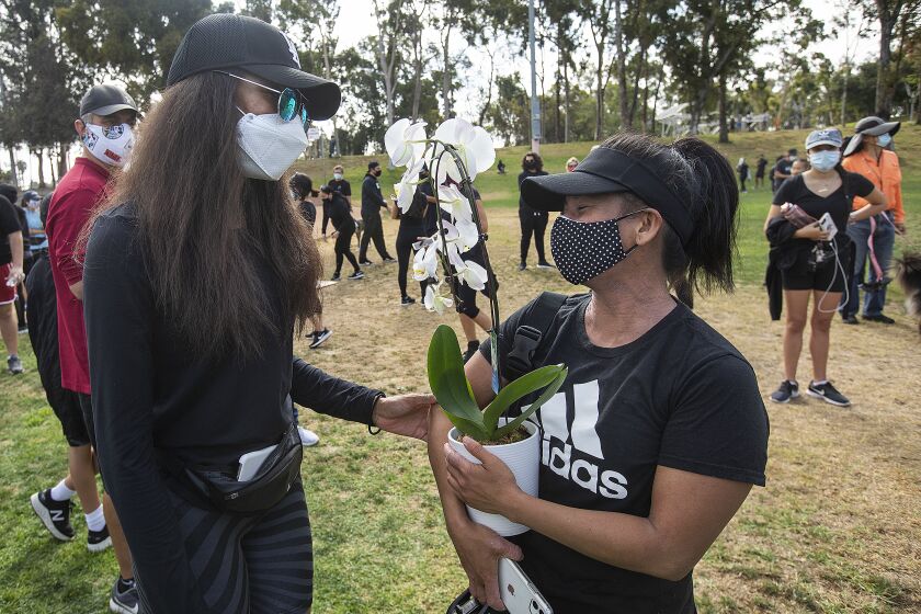 TORRANCE, CA-JUNE 12, 2020: Shannan Tarver, 35, left, of Marina del Rey, talks with Sherry, 38 of Torrance,(she didn't want her last name used), after giving her an orchid, at the conclusion of a rally and workout titled, "We Sweat With You," at Charles H. Wilson Park in Torrance, where a woman made racist, anti-Asian comments to Sherry, as she was exercising in the park, earlier this week. The same woman made anti-asian comments to an Asian male in the driver's seat of his car parked next to hers. (Mel Melcon/Los Angeles Times).