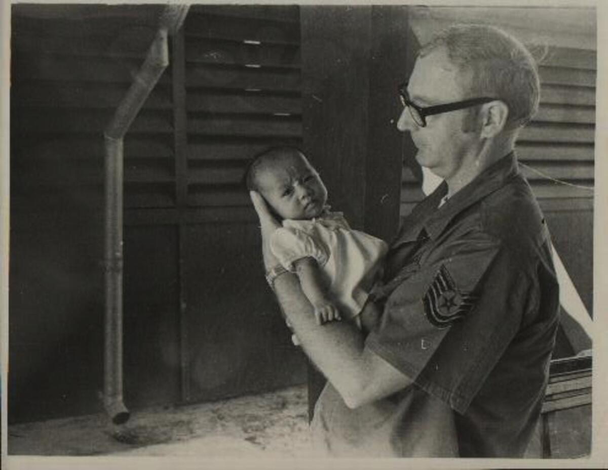 James Mitchell, an Air Force tech sergeant stationed in Vietnam during the war, holds Tran Thi Ngoc Bich. Amid the destruction of war, he hoped to offer her a new life.