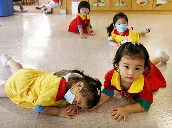 Youngsters wearing masks play at a preschool facility in Hong Kong. The government has ordered all kindergartens and primary schools closed for two weeks after a dozen pupils tested positive for the swine flu in the territory's first local cluster of cases.