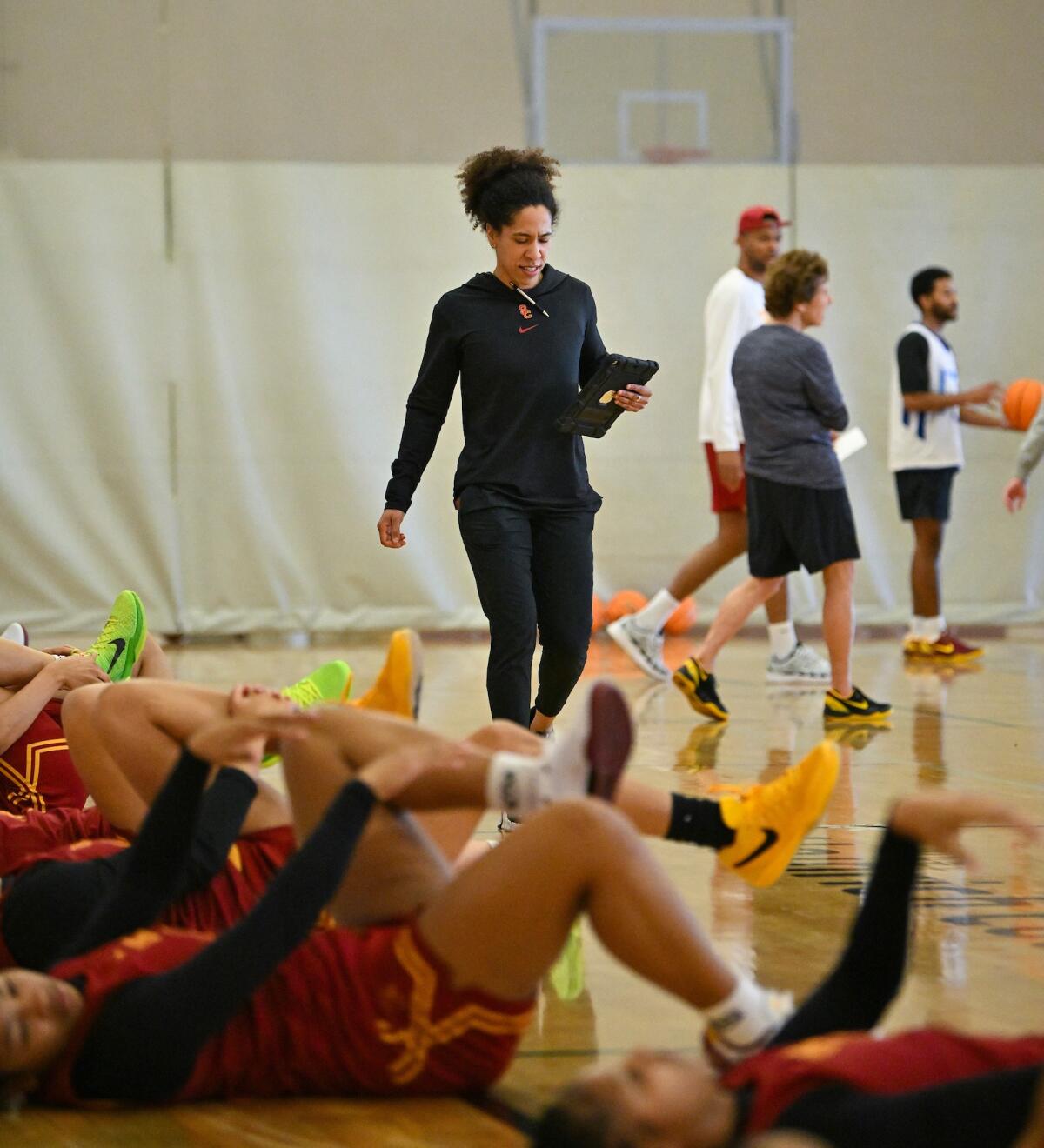 南加州大学女子篮球体能教练凯利·多曼迪在球员们伸展身体时看着她的平板电脑