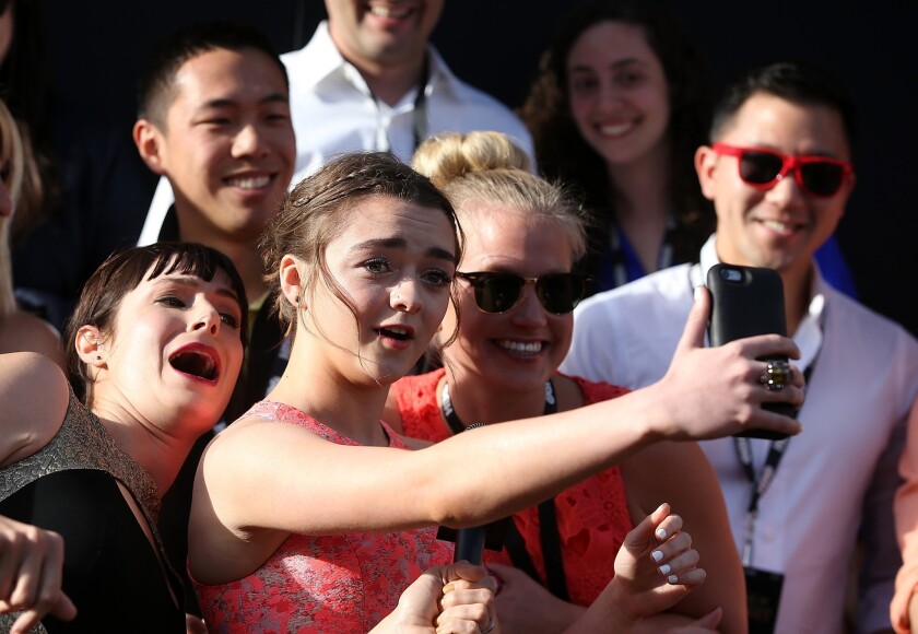 Actress Maisie Williams, center, takes a selfie with fans as she attends the premiere of HBO's "Game of Thrones" at the San Francisco Opera House.