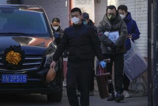 A family member carrying the photo of a deceased relative walks beside a vehicle carrying the body outside a fever clinic in Beijing, Monday, Dec. 19, 2022. Chinese health authorities on Monday announced two additional COVID-19 deaths, both in the capital Beijing, that were the first reported in weeks and come during an expected surge of illnesses after the nation eased its strict "zero-COVID" approach. (AP Photo/Andy Wong)