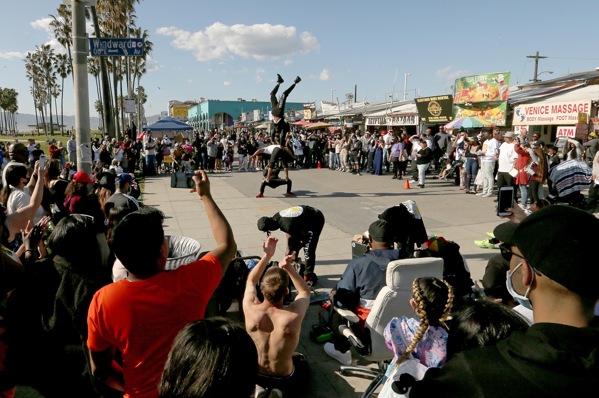 A crowd watches boardwalk performers on Venice Beach. 