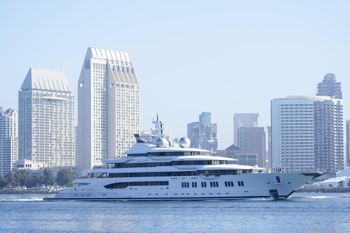 A huge yacht with a city skyline behind it.
