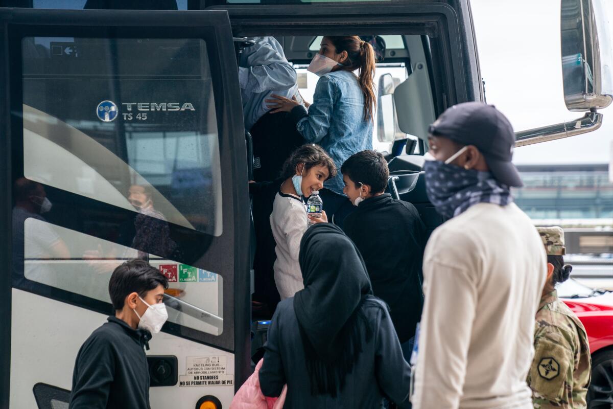 A girl and boy appear to have a staring contest as evacuees board a bus 
