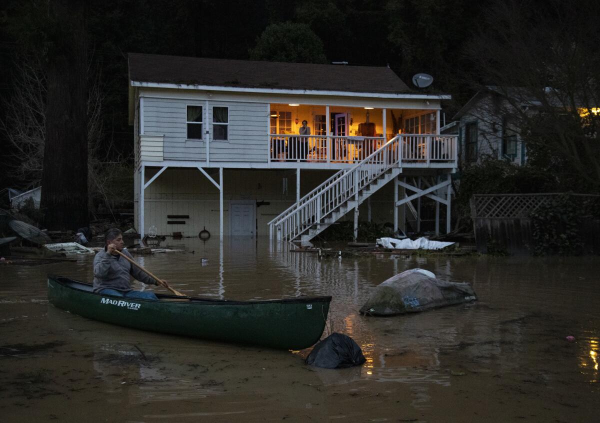 Richard Lopez of Rio Nido, Calif., uses a canoe to retrieve his water scooter, which floated away in the floodwaters in front of his Russian River house.