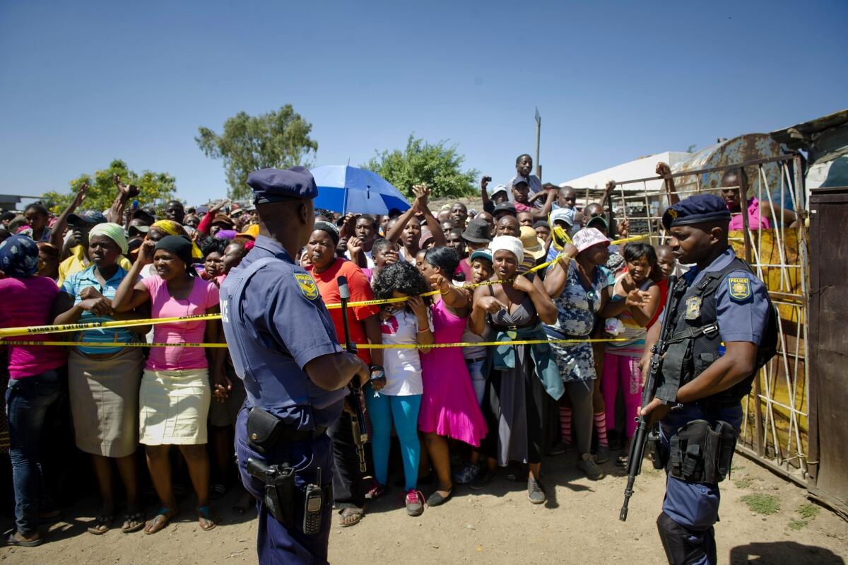 South African police stand guard as residents of Diepsloot township gather near a communal toilet where the bodies of two toddlers were found.