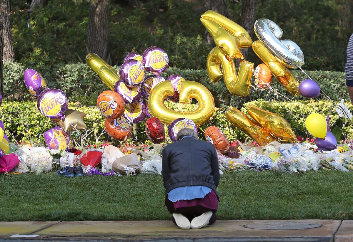 A woman prays Monday at a makeshift memorial for Lakers legend Kobe Bryant outside Pelican Crest, the gated community in Newport Coast where Bryant lived with his family. His daughter Gianna, 13, died with him Sunday in a helicopter crash in Calabasas.