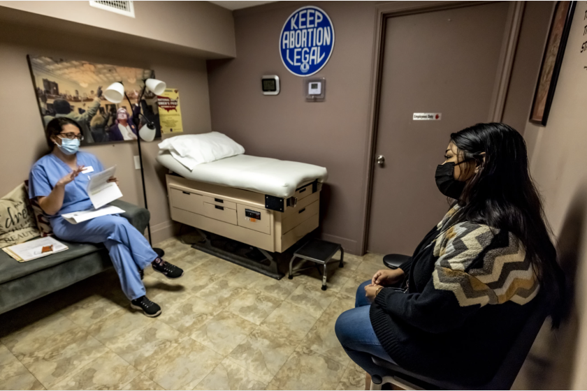 Two women sit across from each other in an exam room.