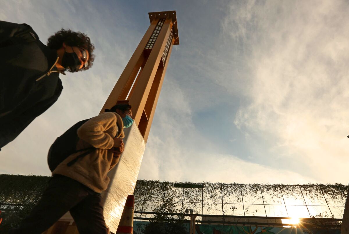 In January, pedestrians walk past one of the columns of the gateway arch in Historic Filipinotown.