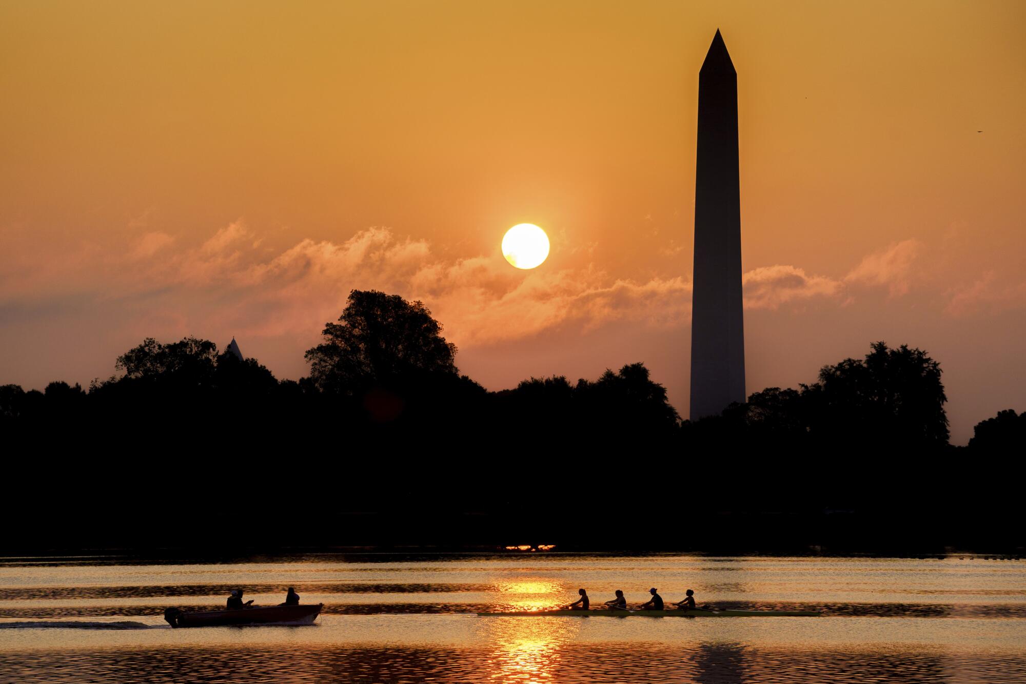 A rowing team glides along the Potomac River past the Washington Monument