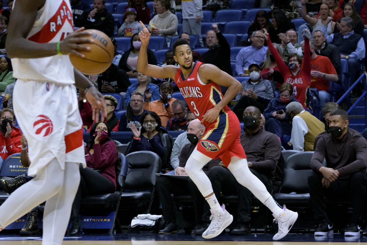 New Orleans Pelicans guard CJ McCollum (3) points to the scoreboard after shooting a 3-point basket against the Toronto Raptors during the second half of an NBA basketball game in New Orleans, Monday, Feb. 14, 2022. (AP Photo/Matthew Hinton)