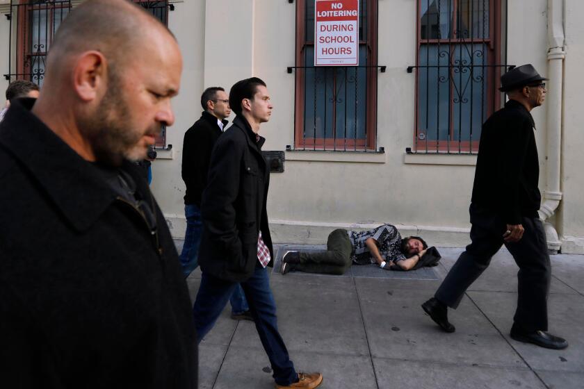 SAN FRANCISCO, CA - SEPTEMBER 10, 2019 - - Del Seymour, right, the unofficial Mayor of the Tenderloin, walks past a sleeping homeless man while leading participants of GLIDEÕs, ÒOfficer and a Mensch,Ó program on a guided tour of the Tenderloin in San Francisco on September 10, 2019. Garrett Hamilton, from left, with the Yolo County DAÕs office, Adam Flores, background, with the Santa Clara County DAÕs office, and San Francisco Police Officer Devan Green participate in the program which tries to instill a greater understanding between law enforcement and the people of historically oppressed communities. Seymour lived homeless for many years in the area. Participants had a full immersion experience dealing with homelessness, addiction, mental illness, poverty and despair in the program. This training is intended to help leaders explore their understanding of the ways traditional government organizations and community-based providers can better ÒserveÓ challenged communities together to improve the quality of life for all of our citizens. (Genaro Molina / Los Angeles Times)