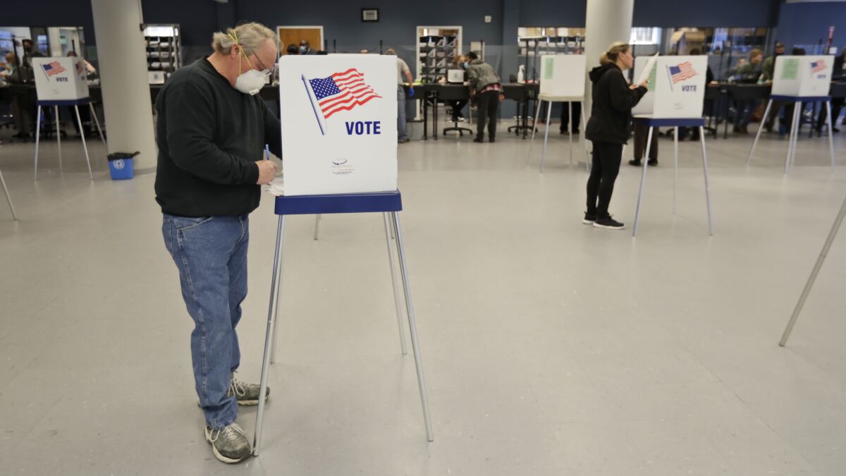 This Tuesday, April 28, 2020 file photo shows Jerome Fedor, left, voting using social distancing at the Cuyahoga County Board of Elections, in Cleveland, Ohio. Ohio's elections chief says his office plans to remove about 120,000 inactive Ohio voter registrations from state voter rolls after the November election. (AP Photo/Tony Dejak, File)