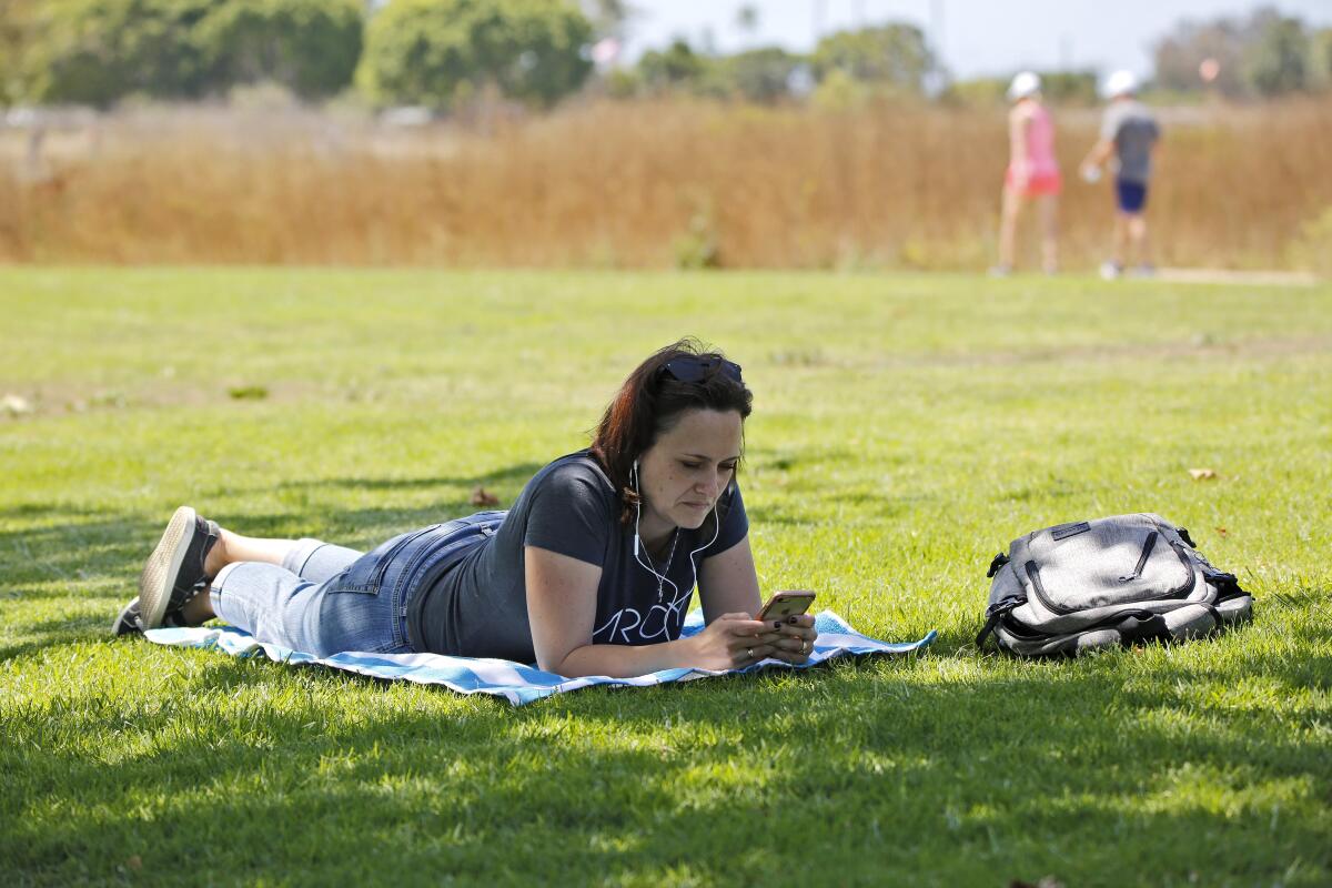 Christine Miller, 41, of Temecula, enjoys a break under a shady tree at Fairview Park in Costa Mesa on Saturday.