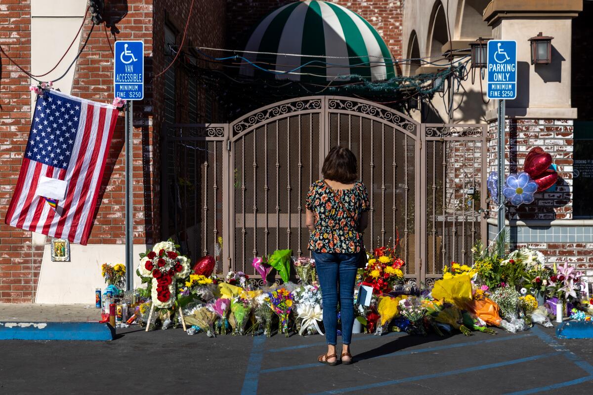 A woman pays her respect at a make-shift memorial for victims of mass shooting outside Star Ballroom Dance Studio.