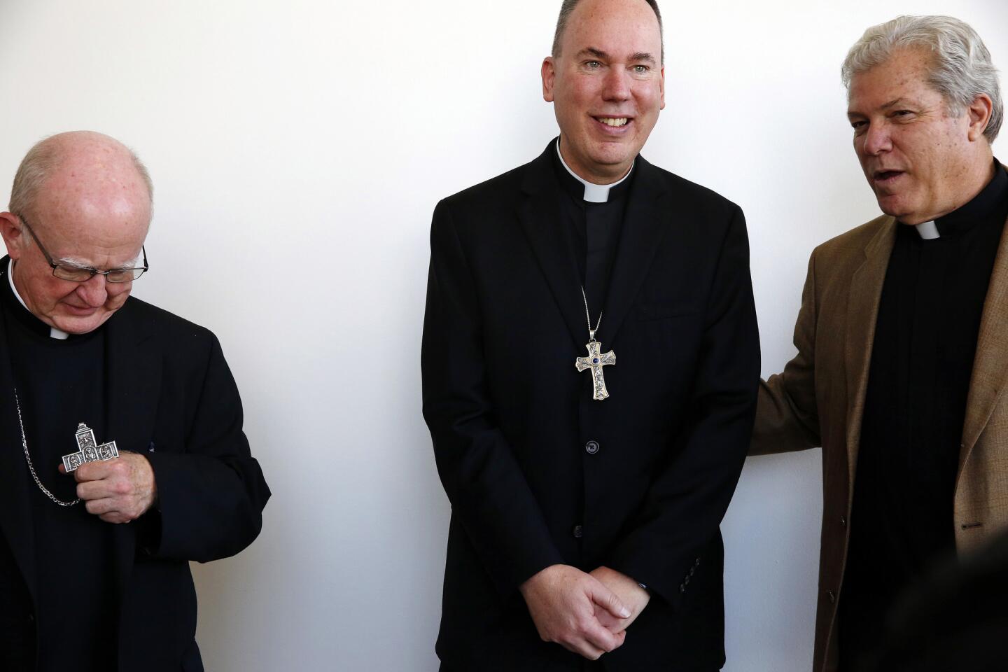 Bishop Kevin Vann, left, the Rev. Timothy Freyer, center, and the Rev. Steve Sallot pose for pictures after a news conference announcing Freyer's appointment by the Holy See as auxiliary bishop for the Diocese of Orange.