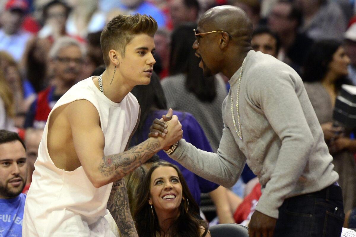 Recording artist Justin Bieber, left, greets boxer Floyd Mayweather Jr. during a Clippers playoff game against the Oklahoma City Thunder at Staples Center.