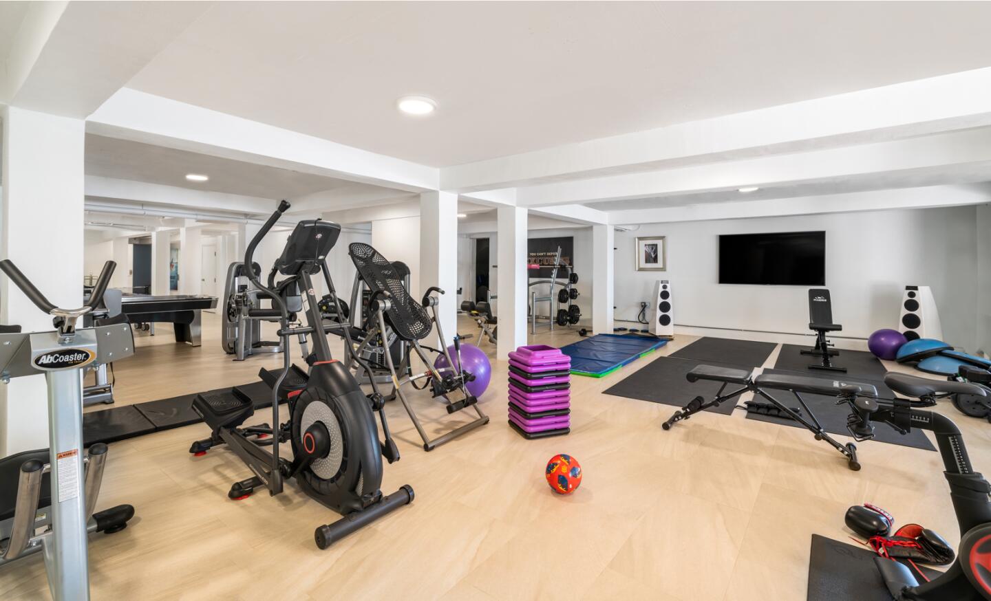 A workout room is spacious with mirrored walls.