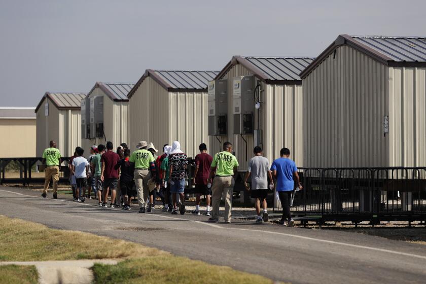 En esta fotografía del 9 de julio de 2019, unos miembros del personal escoltan a unos menores a una clase en un centro de detención para niños migrantes del gobierno de Estados Unidos en Carrizo Springs, Texas. (AP Foto/Eric Gay)