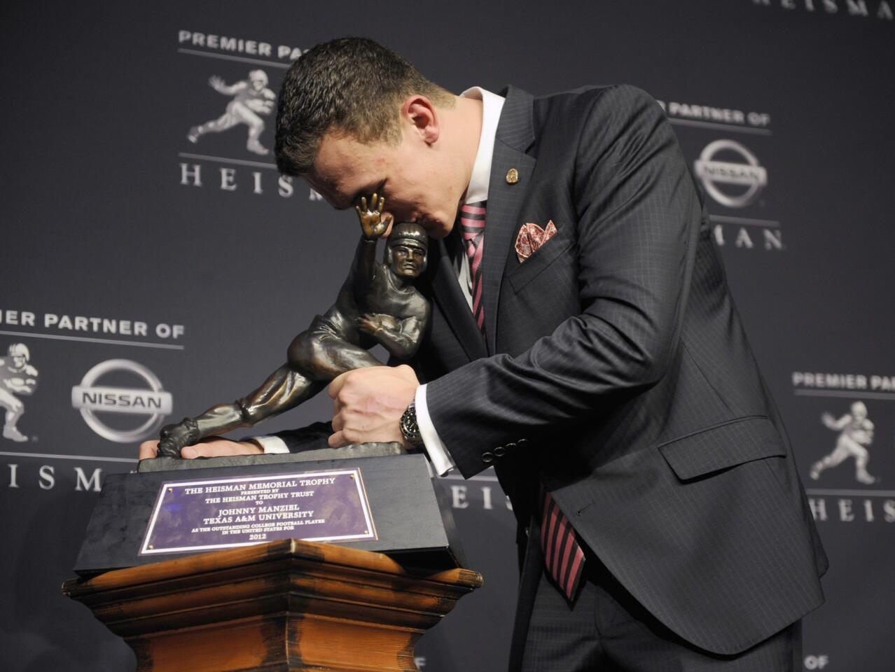 Texas A&M quarterback Johnny Manziel gives the Heisman Trolphy a kiss after becoming the first freshman to win the award on Saturday night at the Best Buy Theater in New York.
