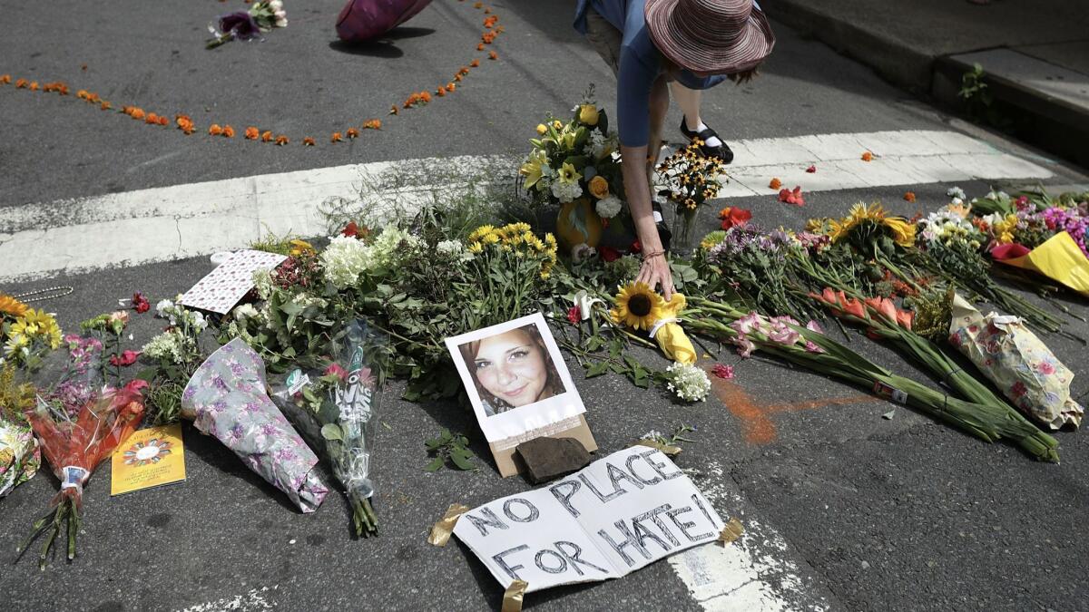 A woman places flowers at an informal memorial to 32-year-old Heather Heyer, who was killed in Charlottesville, Va.