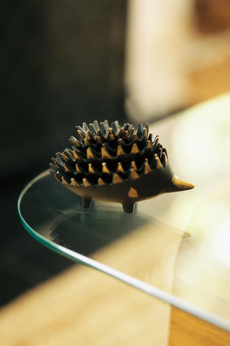 A metal ashtray that looks like a hedgehog, on a glass table