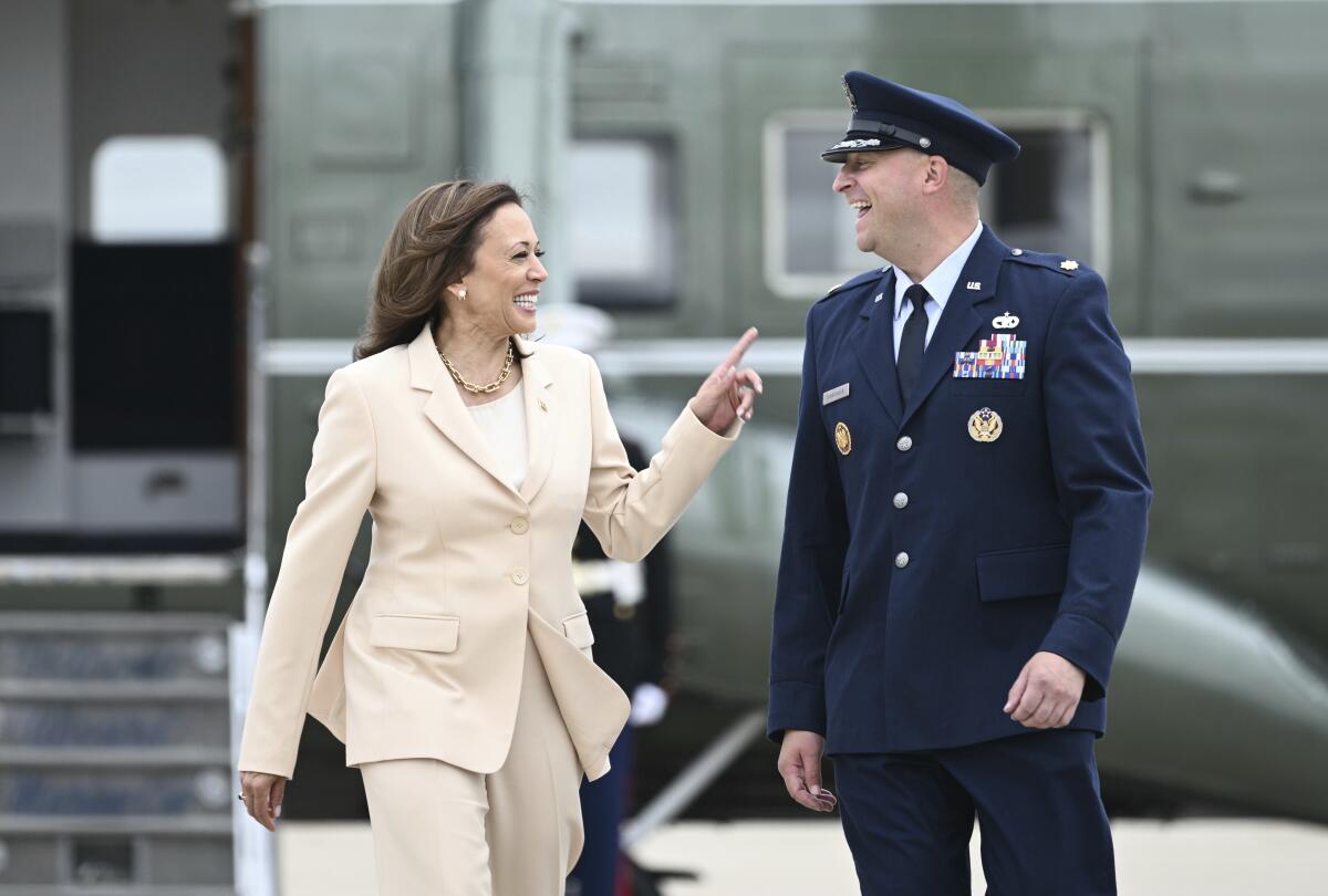 Vice President Kamala Harris speaks to a man in uniform near a plane 