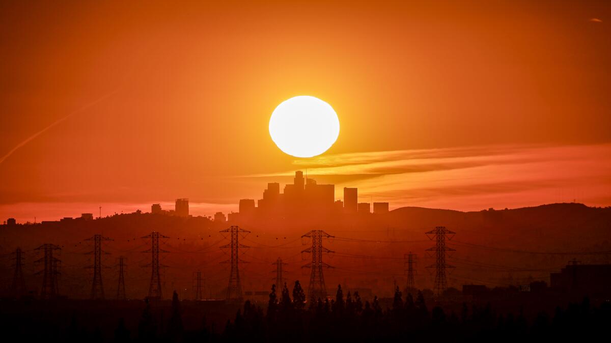 The sun sets behind the L.A. skyline as seen from Azusa.