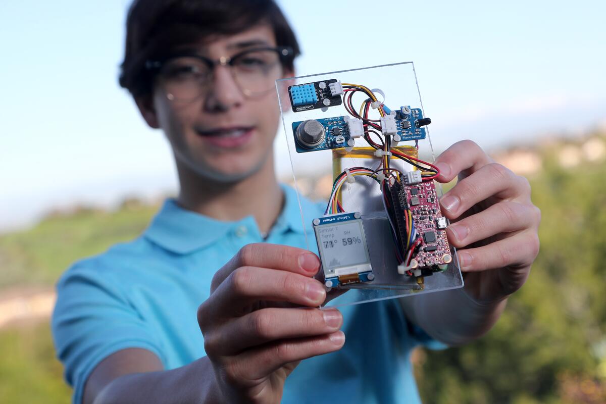 Ryan Honary, 15, a freshman at Newport Harbor, holds up a fire detector.