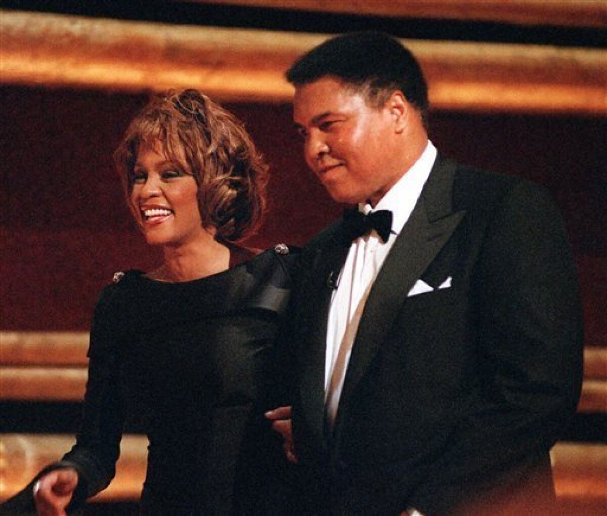 FILE - In this Oct. 21, 1998 file photo, former World Heavyweight Boxing Champion Muhammad Ali is greeted by singer Whitney Houston as he arrives on stage at New York's Radio City Music Hall to accept a GQ "Men of the Year" Award. Whitney Houston, who reigned as pop music's queen until her majestic voice and regal image were ravaged by drug use, has died, Saturday, Feb. 11, 2012. She was 48. (AP Photo/Mitch Jacobson, File)