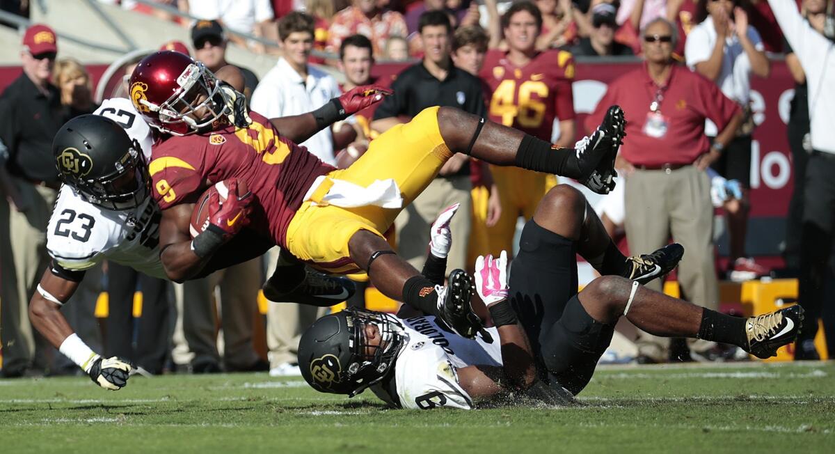 USC receiver Juju Smith is brought down by Colorado defensive players Tedrik Thompson, right, and Ahkello Witherspoon.