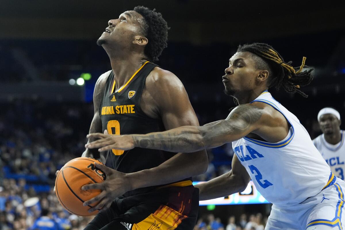 UCLA guard Dylan Andrews, right, reaches with his left hand to try to steal the ball from ASU center Shawn Phillips Jr.