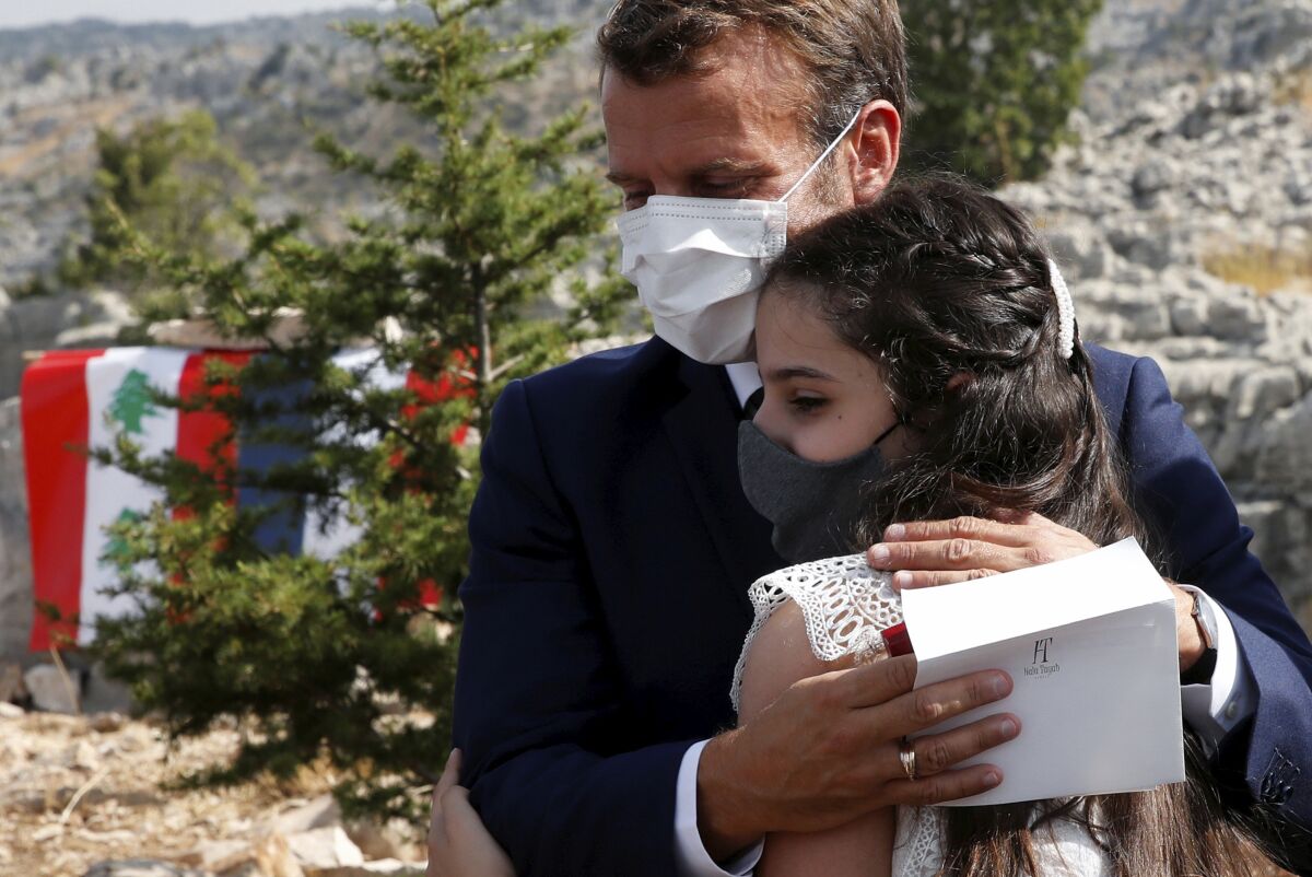 French President Emmanuel Macron hugs blast victim Tamara Tayah after planting a cedar with members of the NGO Jouzour Loubnan in Jaj, near Beirut, Tuesday Sept. 1, 2020. French President Emmanuel Macron returned to Lebanon on Monday, a country in the midst of an unprecedented crisis, for a two-day visit and a schedule packed with events and political talks aimed at charting a way out for the country. (Gonzalo Fuentes/Pool via AP)