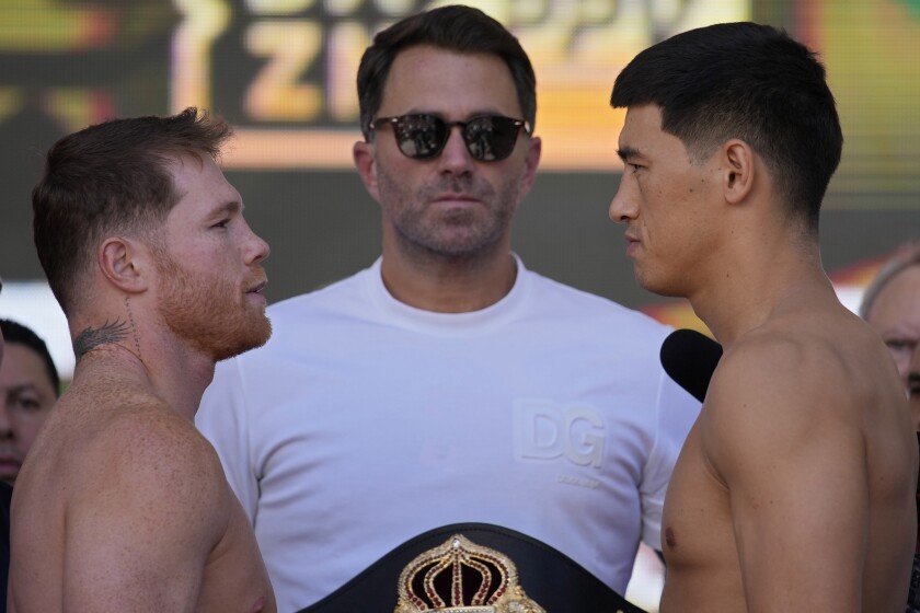 Canelo Álvarez, left, and Dmitry Bivol, right, stare at each other during a weigh-in on May 6, 2022.