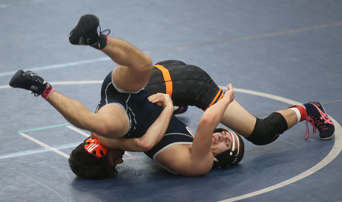 Huntington Beach's William Krcelic, on top, tries to roll Newport Harbor's Luis Nateras in a 138-pound match of the Wave League dual meet in Newport Beach on Wednesday.