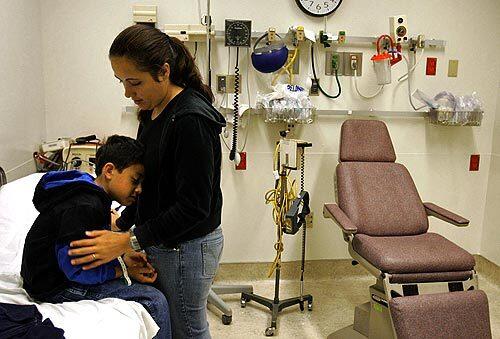 A CLOSE CALL: Nodrigo Plata, 6, leans against his mother, Naty Mercado, in the emergency room of Downey Regional Medical Center. The hospital had considered closing the ER a year ago, but a new Medi-Cal reimbursement contract kept it open.