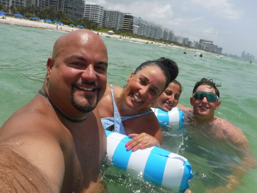 This Wednesday, June 23, 2021, photo provided by Albert Aguero shows him, his wife, Janette; 14-year-old daughter, Athena, and 22-year-old son, Justin Willis, vacationing in the Miami area from New Jersey. They all were able to escape the building collapse of Champlain Towers South the following day. “When I opened the staircase door and half the staircase was missing, at that point I know we’re racing against time to all get out as a family,” Albert Aguero says. (Albert Aguero via AP)