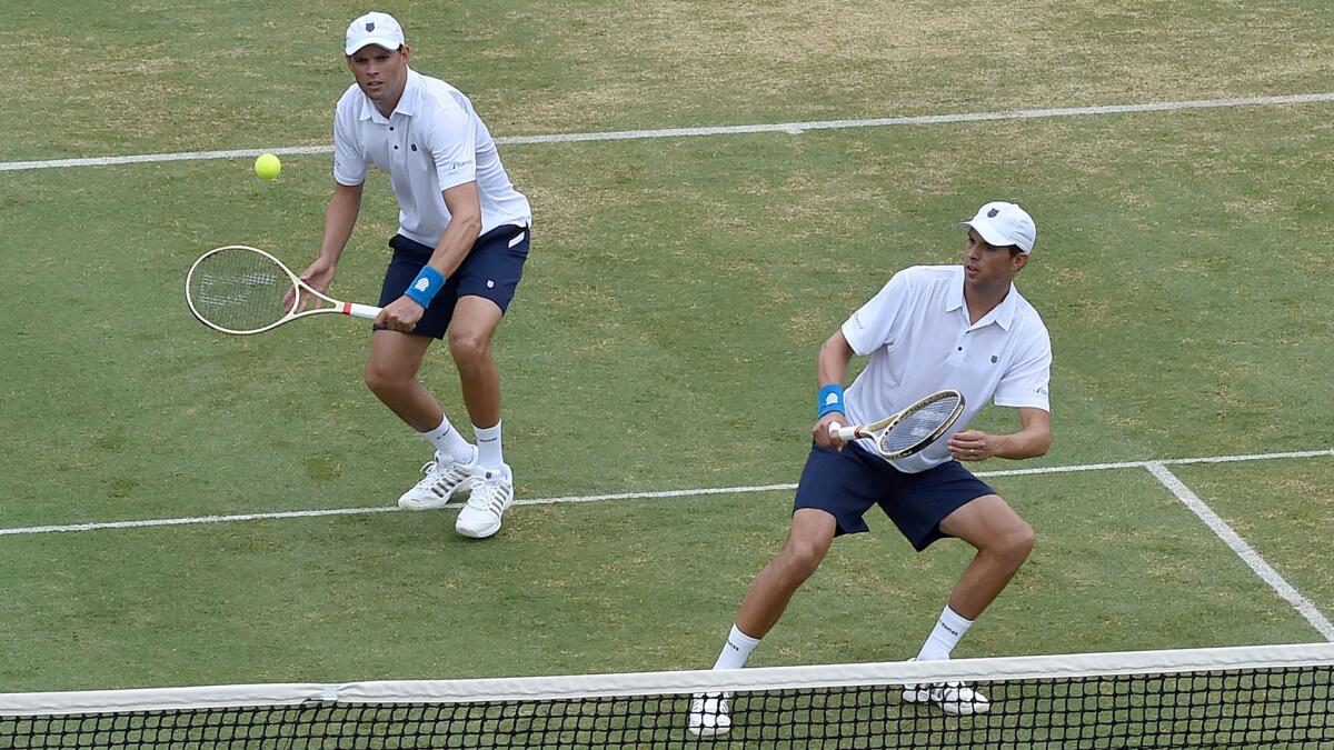 Bob Bryan plays a shot as his twin brother Mike leans out of his way during a David Cup double match Friday.