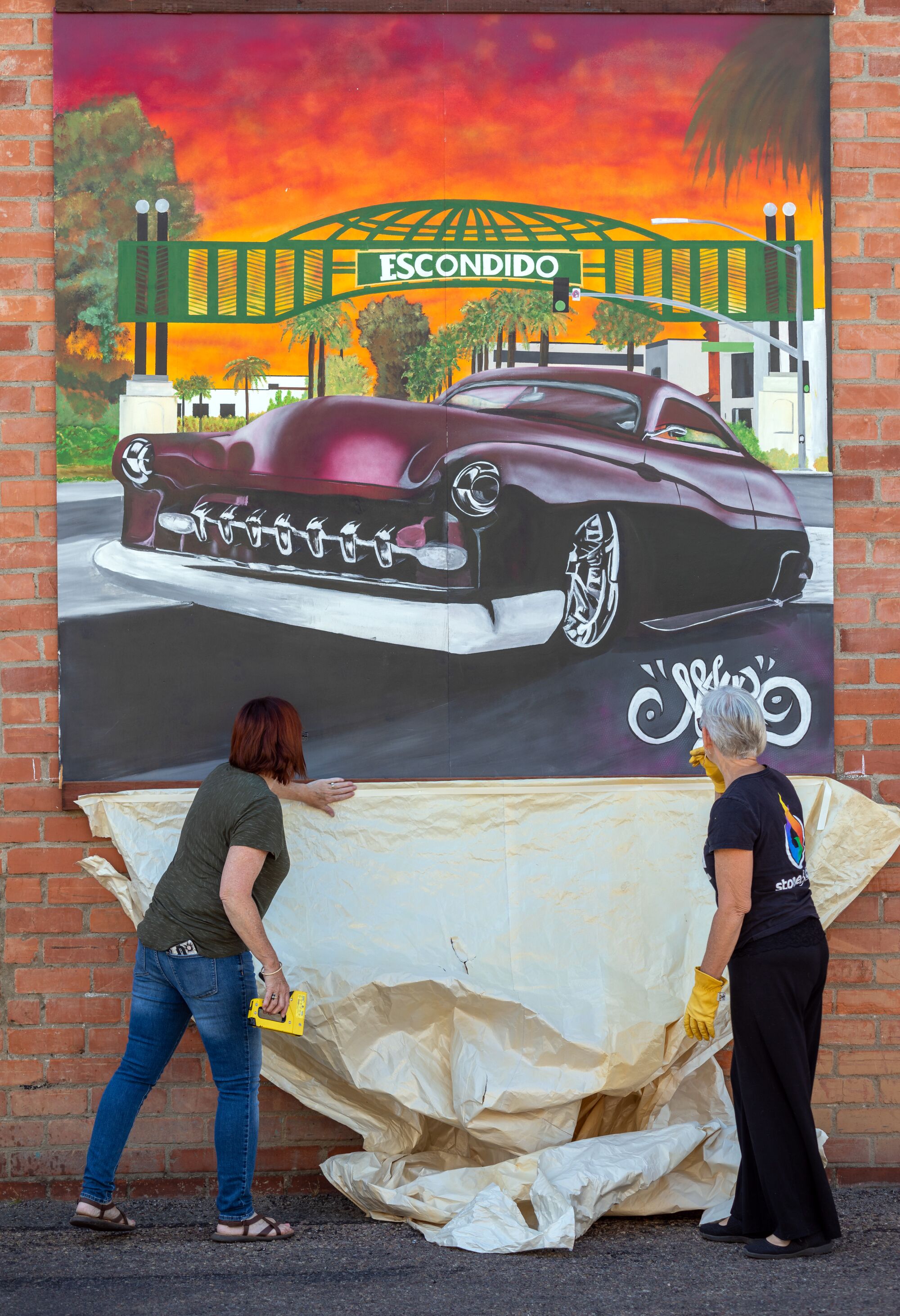Escondido Art Association committee members Heather Moe and Carol Rogers install artist mural panels